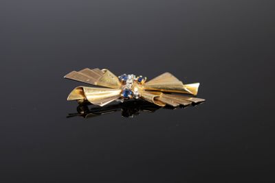 une broche en forme de nœud dorée sur un fond noir