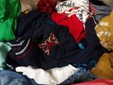 a pile of clothes sitting on a bed next to a pillow
