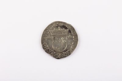 une vieille pièce d'argent sur laquelle figure une couronne, posée sur un fond blanc