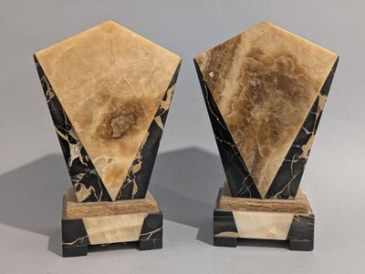 une paire de vases en marbre noir et blanc posés sur des socles, sur fond gris