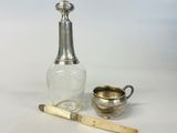 une image représentant une bouteille en argent et en verre à côté d'une coupe en argent