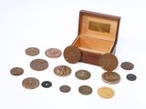 une petite boîte en bois remplie de pièces de monnaie posée sur une surface blanche