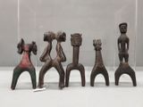 quatre figurines en bois de formes et de tailles différentes, présentées dans une vitrine