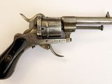 un vieux revolver avec une poignée en bois sur une surface blanche