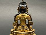 brass statue of a person sitting in a lotus position on a pedestal