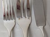 three forks and a knife sitting on a table
