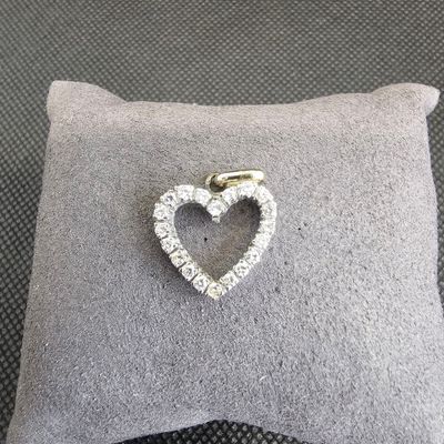 un gros plan d'une broche en diamant en forme de cœur posée sur un coussin