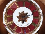 a clock with a red and gold face in a wooden box
