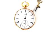 a gold pocket watch and a key on a white surface