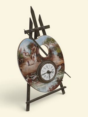 une horloge posée sur un chevalet sur lequel est posé un tableau