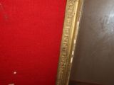 a mirror with a gold frame on a red wall