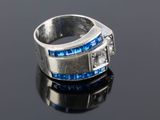a close up of a silver ring with blue stones on a black surface