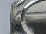 a silver plate with a silver handle on a white table