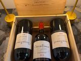 three bottles of wine in a wooden box on a table