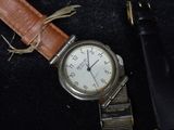 a watch that is sitting next to a pen on a table