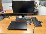a desk with a laptop, keyboard, mouse, and monitor on it