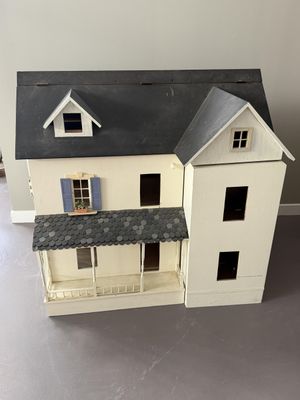 une maison de poupées blanche avec un toit noir et deux fenêtres