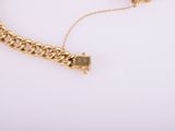 a gold chain bracelet with a heart charm on a white background