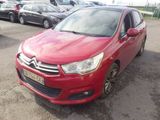 La voiture rouge est garée sur le parking, à côté d'autres voitures.