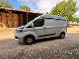 a silver van parked in front of a barn with hay bales
