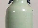 a green vase sitting on a table with a white wall in the background