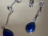 une paire de boucles d'oreilles en pierre bleue avec des crochets en argent, posée sur une table