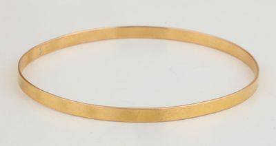 gros plan d'un bracelet en or sur une surface blanche