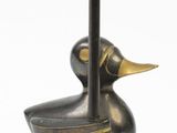 a bronze duck with a pencil in its beak