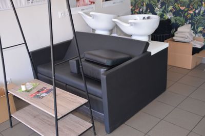 a picture of a salon with a black couch and a white sink