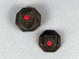 deux boutons en plastique noir et rouge posés sur une surface blanche