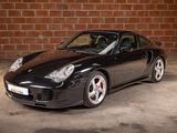 a picture of a black sports car parked in front of a brick wall