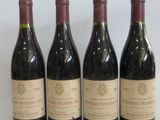 four bottles of wine are lined up on a white surface