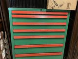 une commode verte et rouge surmontée d'une boîte