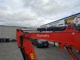 an image of a red excavator parked in front of a building