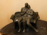 une statue en bronze représentant une femme assise sur un banc
