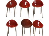 six red plastic chairs with chrome legs and a white background