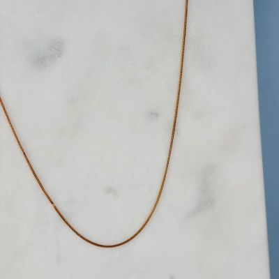 a close up of a gold chain on a marble slab