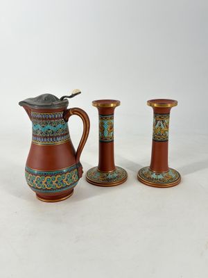 trois vases marron et bleus posés les uns à côté des autres sur une surface blanche