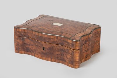 an antique wooden box with a silver button on the lid
