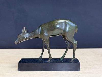 une image représentant une statue en bronze d'un cerf posée sur un socle noir