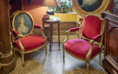 deux chaises rouges dans un coin d'une pièce où est accroché un tableau au mur