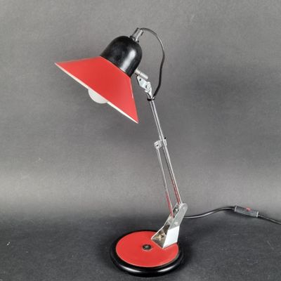 une lampe de bureau noire et rouge posée sur une surface noire