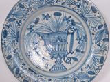 a blue and white plate with a vase on it