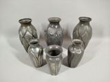 five vases sitting in a circle on a white surface