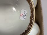 a close up of a white and gold vase with a tag on it