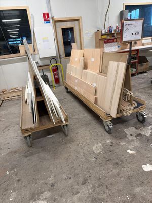 Plusieurs morceaux de bois sont empilés sur un chariot dans une pièce