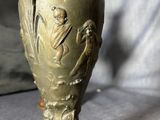 a bronze vase with a bird on top of it