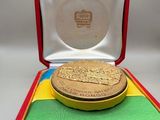 une image représentant une médaille d'or dans un écrin rouge