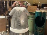 une statue représentant une femme en robe et un ours en peluche posés sur une table