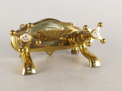 une figurine en or représentant une vache posée sur une table blanche
